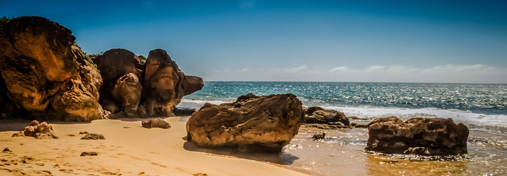 Large rocks on a beach with the ocean in the background